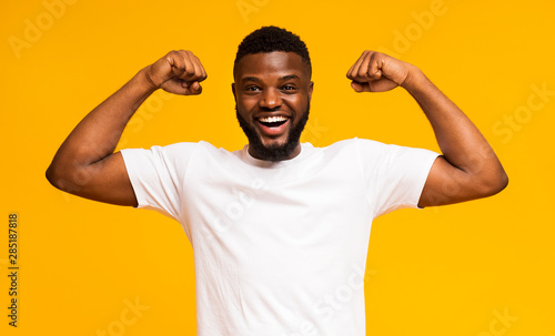 African american man smiling and showing biceps at camera