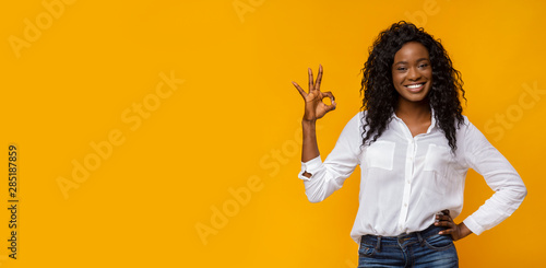 Happy black woman gesturing OK sign and smiling
