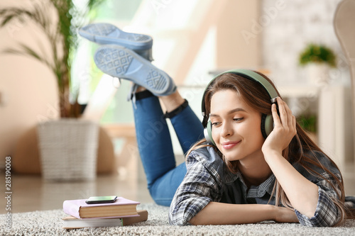 Beautiful young woman listening to audiobook at home photo