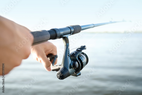 Young man fishing on river, closeup