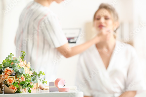 Bouquet of flowers and box with ring on table of young bride preparing for wedding