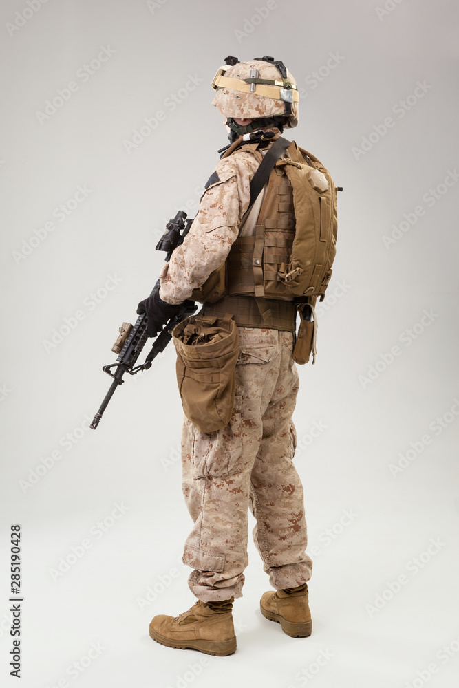 Soldier in US marines uniform with rifle on light grey background, studio shot Soldier in US marines uniform with rifle on light grey background, studio shot