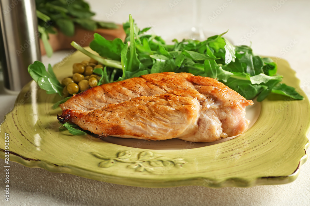 Plate with tasty arugula salad and chicken on table Plate with tasty arugula salad and chicken on table