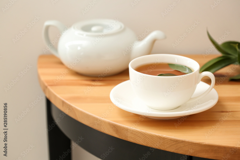 Cup of hot beverage and teapot on table Cup of hot beverage and teapot on table