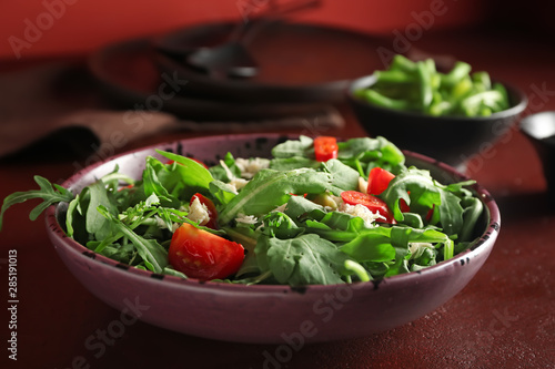 Plate with tasty arugula salad on table