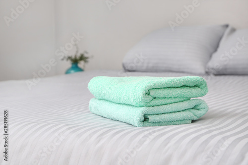Stack of clean towels on bed © Pixel-Shot