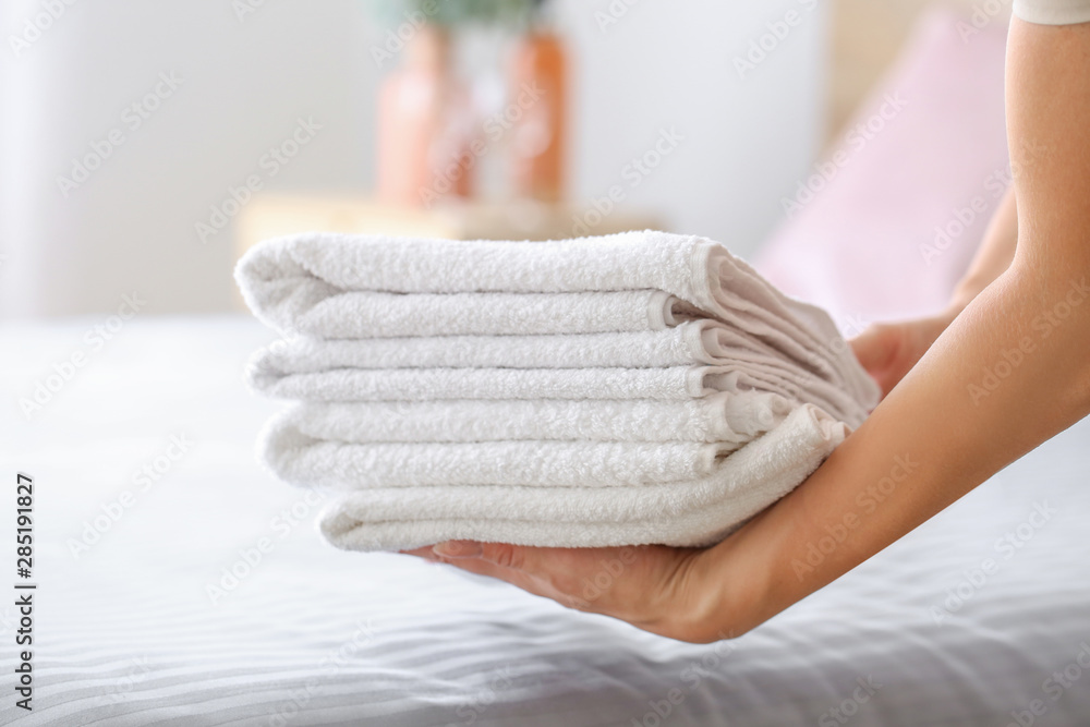 Female housekeeper putting clean towels on bed Female housekeeper putting clean towels on bed