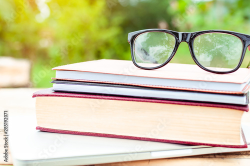 Vintage book and eye glasses for read and write over blurred nature outdoor background with copy space,selective focus ,education concept