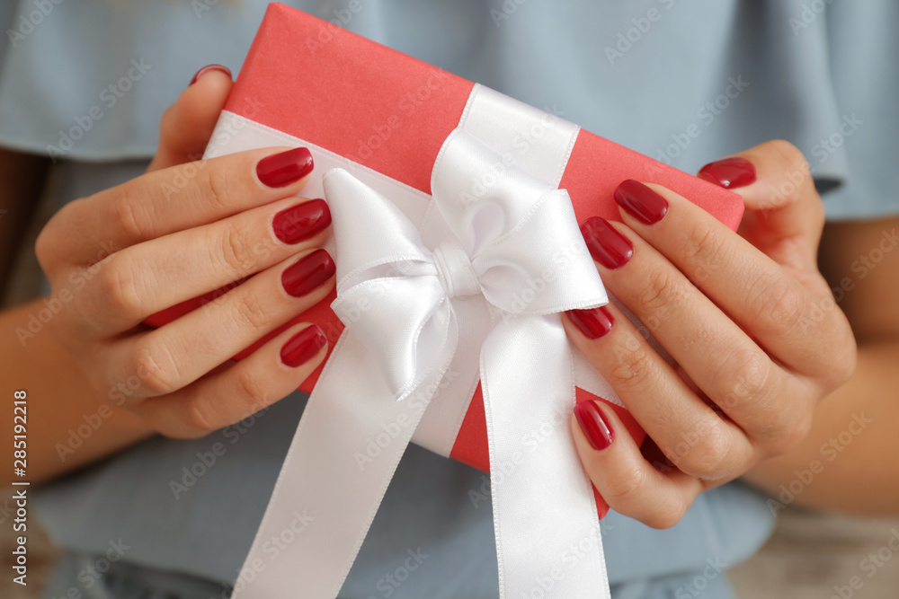 Woman with beautiful manicure holding gift box, closeup Woman with beautiful manicure holding gift box, closeup