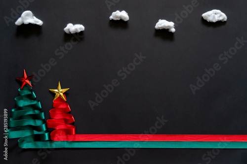 Christmas trees made from green and red ribbon with gold star on black background with coppy space
