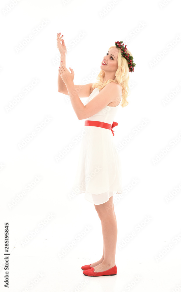 full length portrait of blonde girl wearing a white dress and flower crown. Standing pose, isolated against a white studio background. full length portrait of blonde girl wearing a white dress and flower crown. Standing pose, isolated against a white studio background.