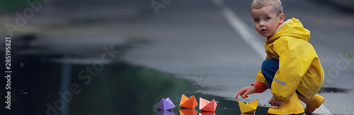 a boy plays boats in a puddle / childhood, walk, autumn game in the park, a child on a walk