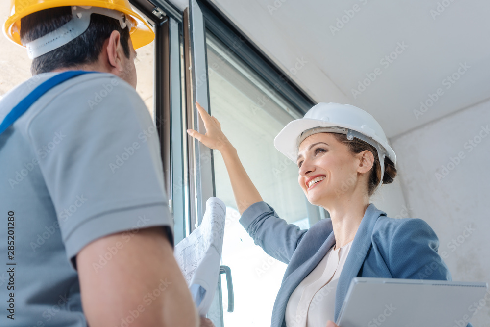 Architect and construction worker checking windows on site Architect and construction worker checking windows on site