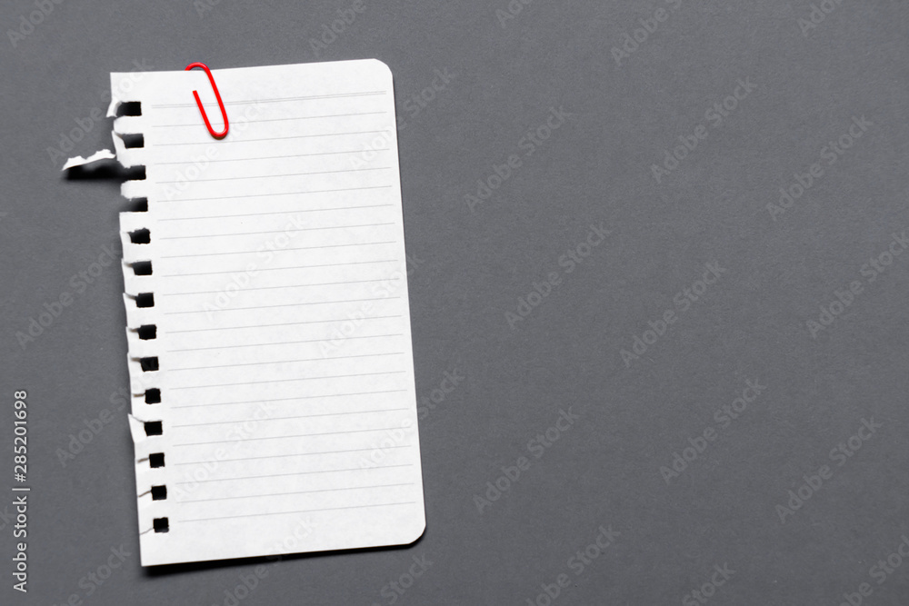 Empty paper sheet with white texture and pink paper clip on gray background surface. Copy space for add text or art work designs.