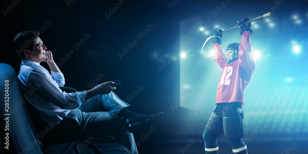 Fototapeta premium Young man watching ice hockey game on TV