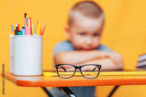 boy sitting ubfocused glasses in focus. Concept problem of ophthalmology correction of myopia. back to school. Selective focus. upset child