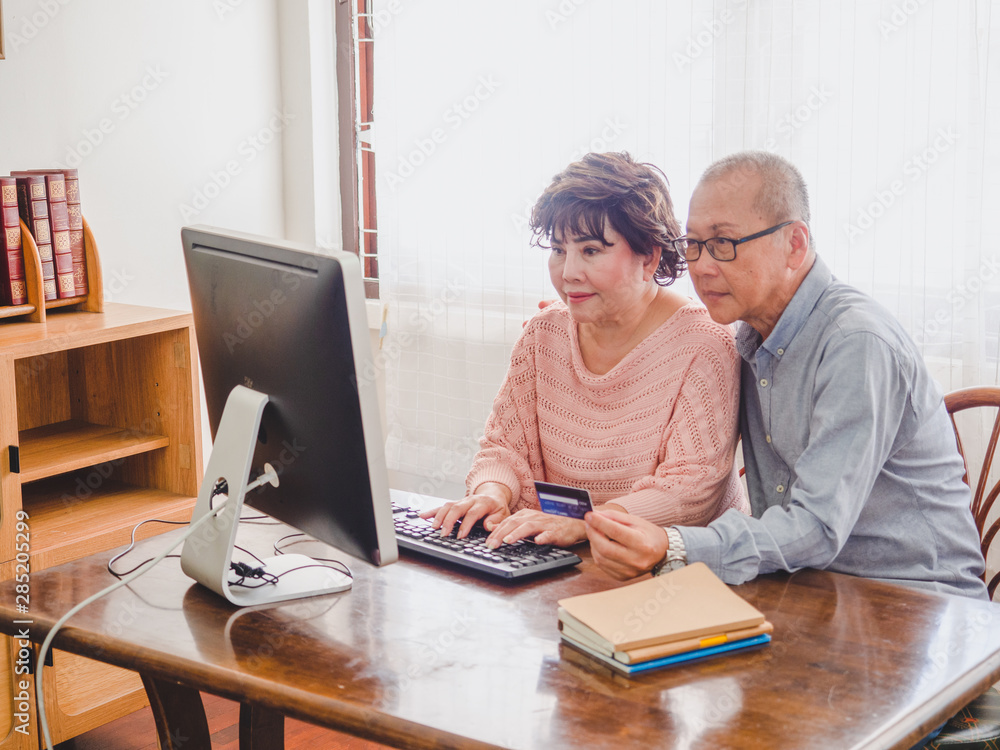 elder couple using computer together with credit card at home elder couple using computer together with credit card at home
