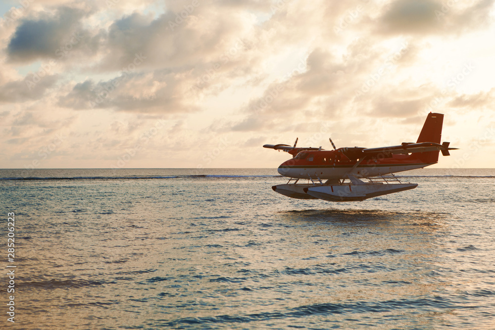 Summer sunset with seaplane. Landing seaplane on the dawn seashore. Calm scenery on evening sea. Summer sunset with seaplane. Landing seaplane on the dawn seashore. Calm scenery on evening sea.