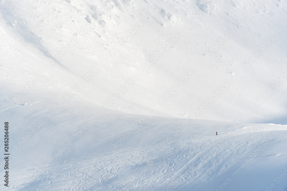 Lonely skier resting on the mountains in a ski resort. The tiny skier gives a sense of scale.