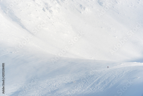 Lonely skier resting on the mountains in a ski resort. The tiny skier gives a sense of scale. © Niccolo