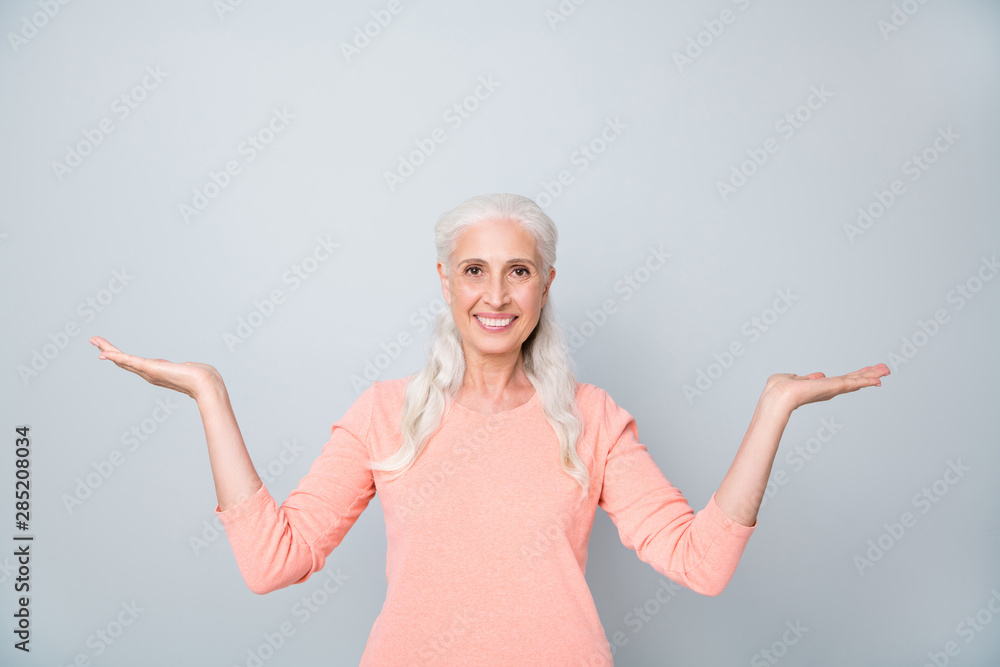 Close up photo of confident smart clever intelligent granny holding invisible objects products on palms isolated grey background Close up photo of confident smart clever intelligent granny holding invisible objects products on palms isolated grey background