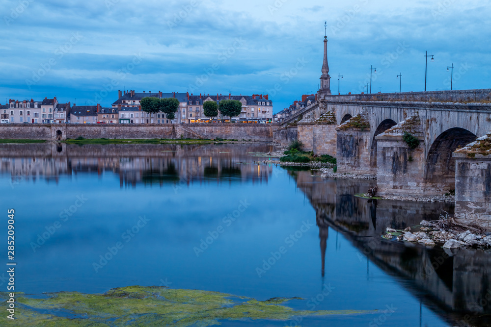 Twilight view of Jacques Gabriel bridge and city skyline reflected in water of Loire river. Blois, France.	