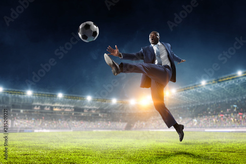 Black businessman in a suit playing footbal photo