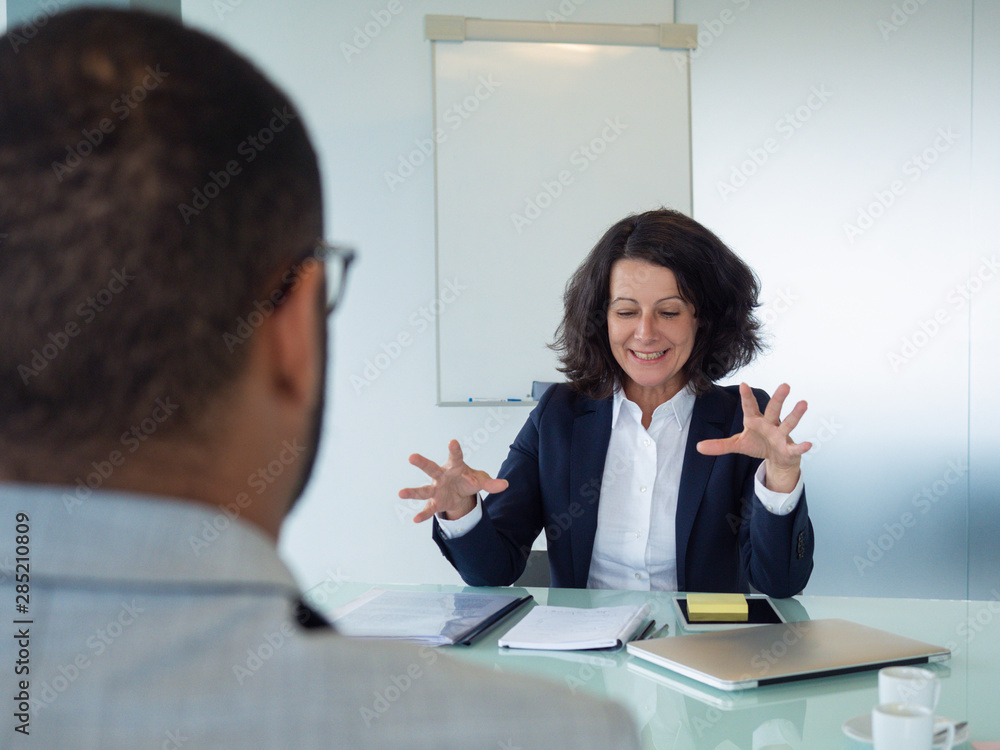 Human resource manager interviewing male applicant. Business man and woman sitting at table opposite of each other, woman excited with conversation and gesturing. Job interview concept Human resource manager interviewing male applicant. Business man and woman sitting at table opposite of each other, woman excited with conversation and gesturing. Job interview concept