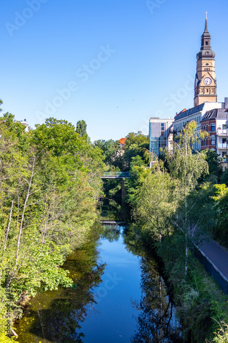 Picture from the Karl Heine Canal in the scene district Plagwitz in leipzig between center and lindenauer harbor with bike path, old and modern houses and church