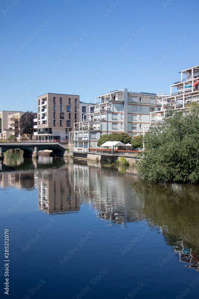 Obraz premium Modern residential buildings in Leipzig scene district Schleussig directly on the river Elster with bridge with blue sky and sunshine