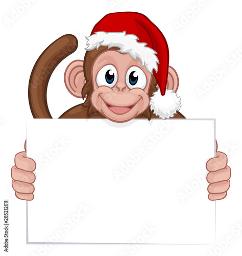 A Christmas monkey animal cartoon character in a Santa hat holding a sign