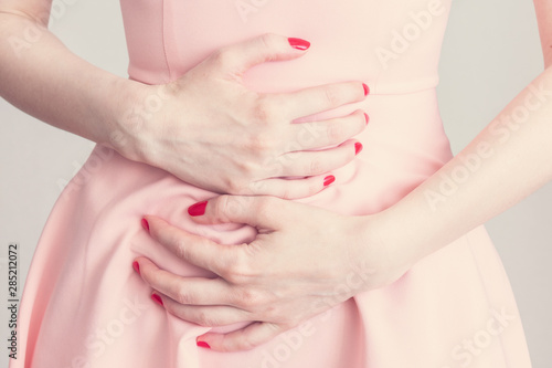 The woman had a stomach attack, ulcer or gastritis, woman's hands, close up, cropped image, toned