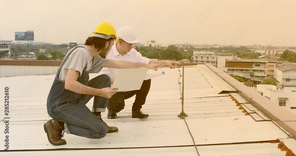 Asian engineers sitting on rooftop, they discuss about blueprint and handshake. Asian engineers sitting on rooftop, they discuss about blueprint and handshake.