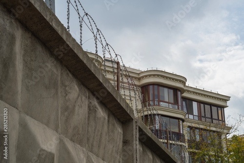 A fragment of a house behind a high concrete fence and barbed wire
