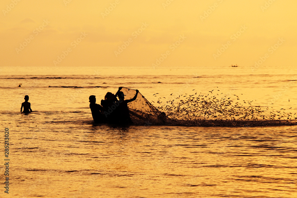 fisherman fishing with net	during sunset