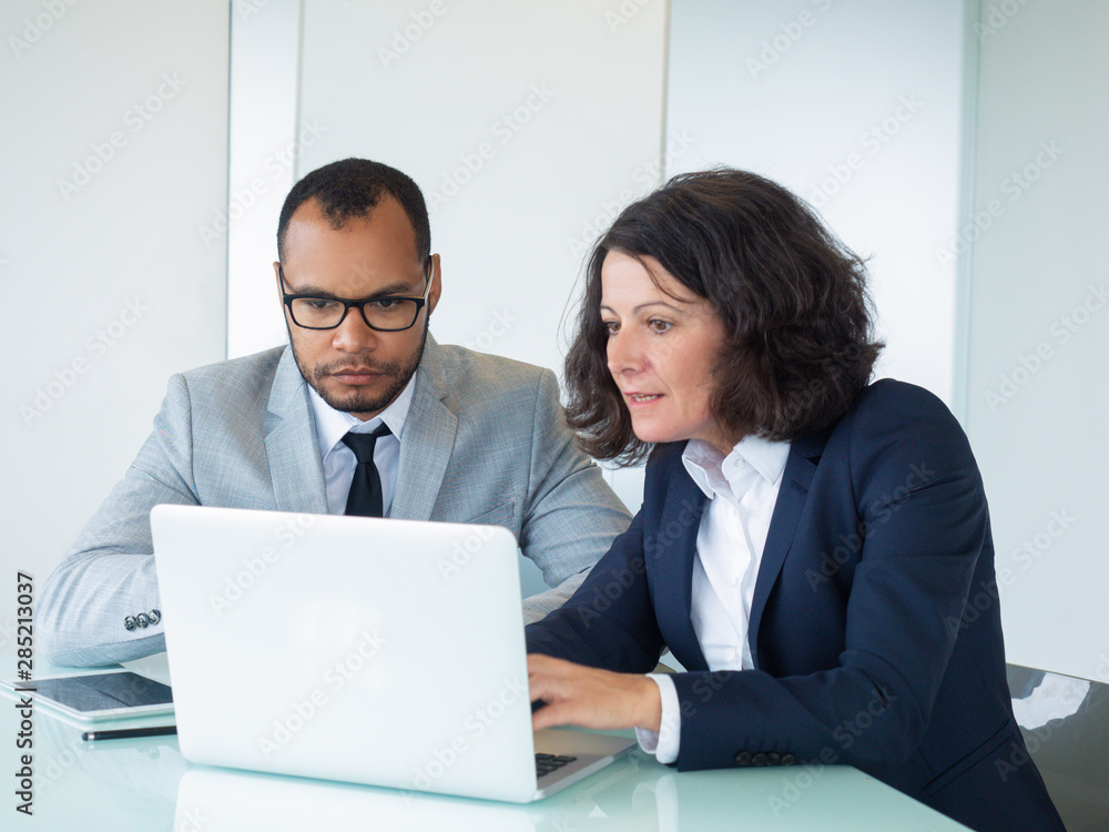 Excited business team working on project together. Business man and woman sitting at office table, using laptop and staring at screen. Business team concept Excited business team working on project together. Business man and woman sitting at office table, using laptop and staring at screen. Business team concept