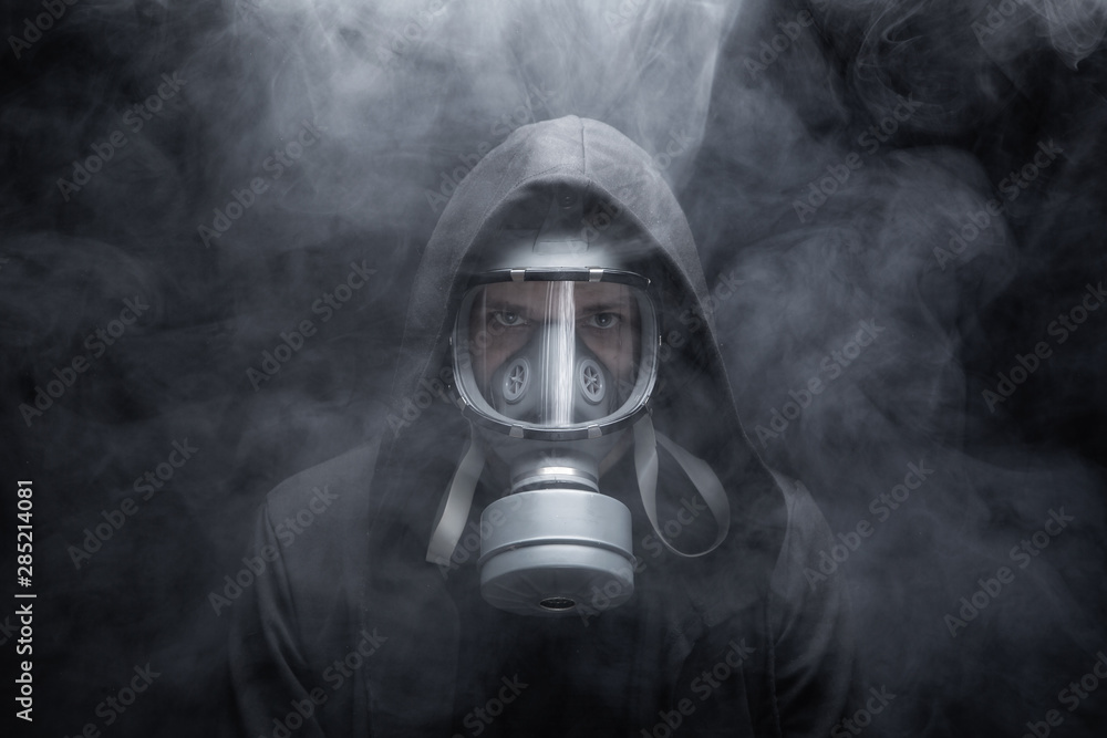 Man wears a respirator in a smokey, toxic atmosphere. Black background. Man wears a respirator in a smokey, toxic atmosphere. Black background.