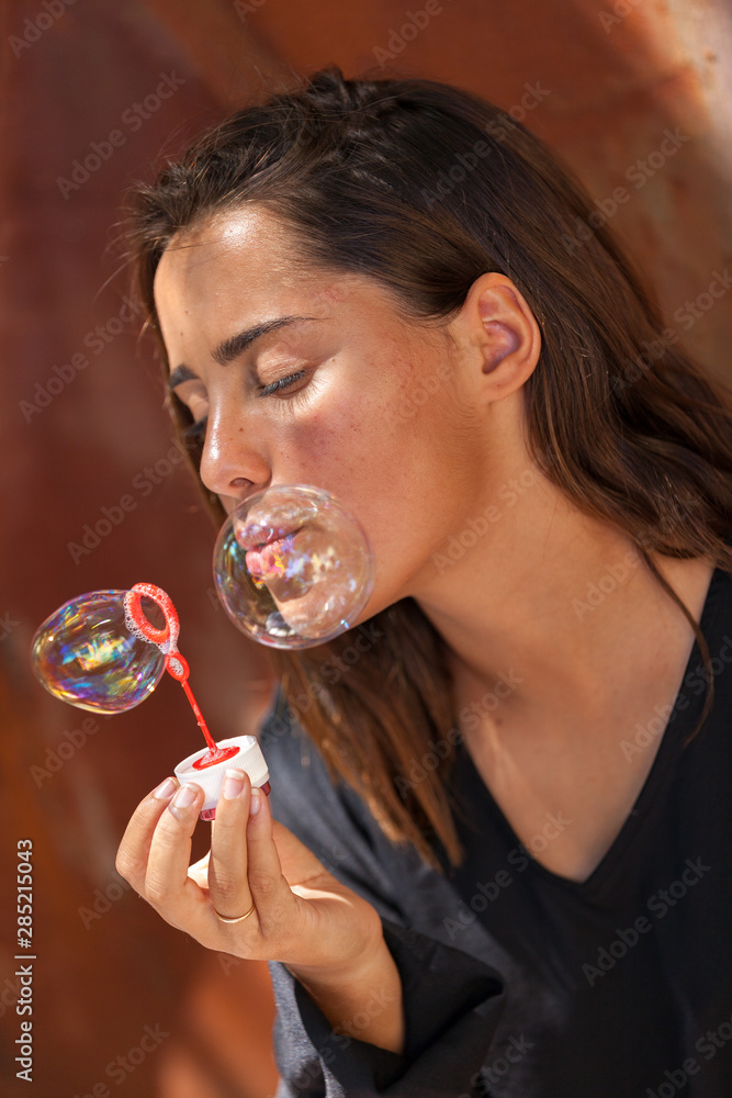 Beautiful young woman with black blouse blowing soap bubble.. Beautiful young woman with black blouse blowing soap bubble..