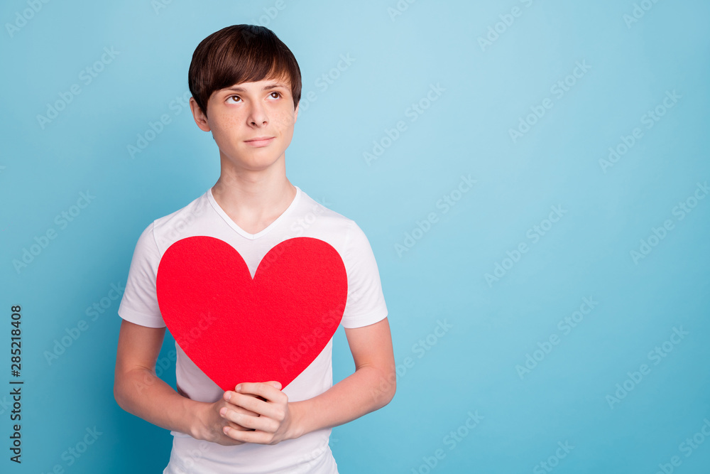 Photo of handsome boyfriend holding red paper heart waiting to be presented to boy girlfriend while isolated with blue background Photo of handsome boyfriend holding red paper heart waiting to be presented to boy girlfriend while isolated with blue background