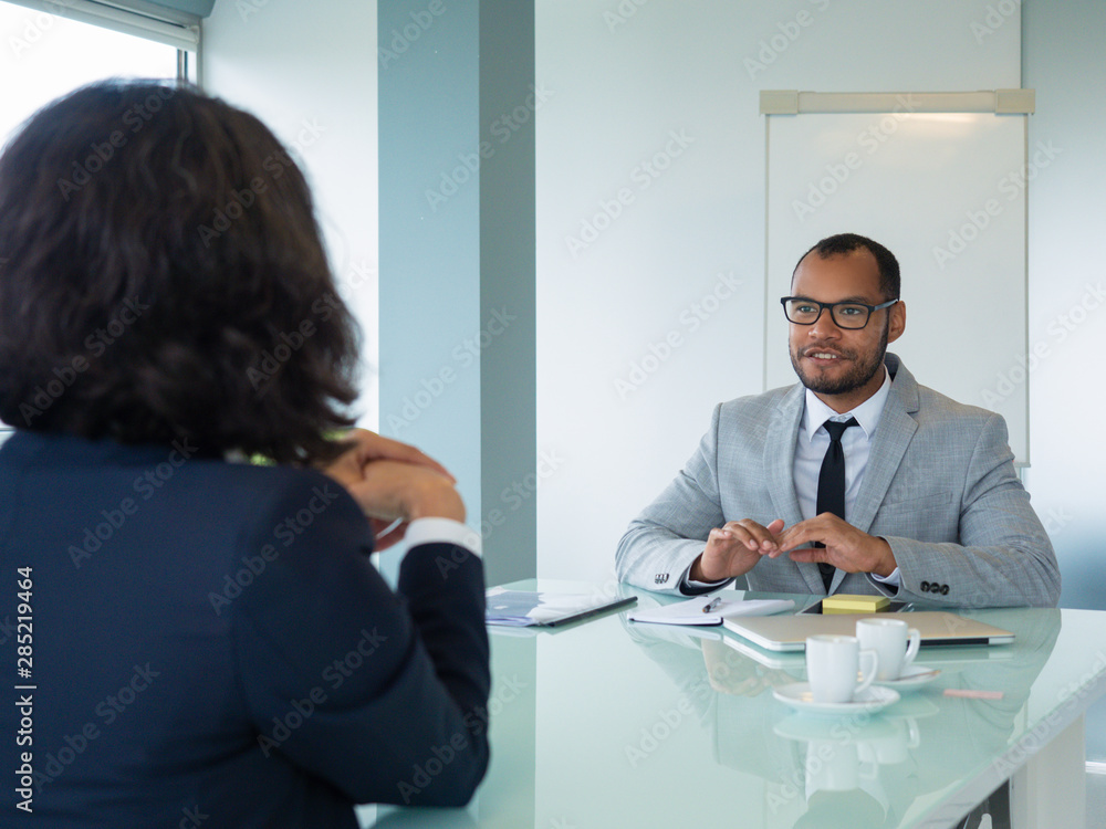 Obraz premium Confident male business leader talking to female job candidate. Business man and woman sitting at conference table opposite of each other. Employment concept