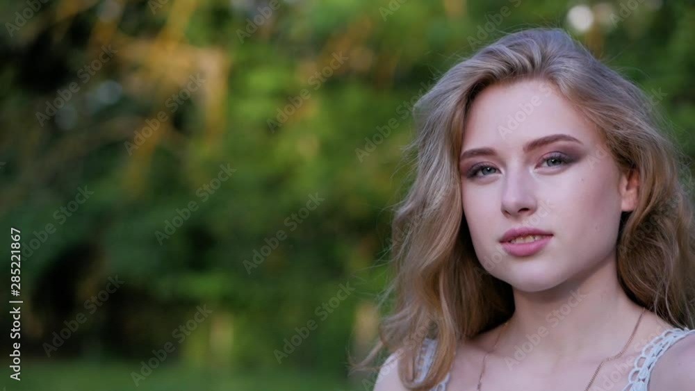 Portrait of a beautiful young girl with blond hair looking at camera. Slow motion. Portrait of a beautiful young girl with blond hair looking at camera. Slow motion.