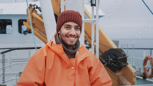 Foto Portrait of Dressed in Bright Protective Coat Smiling on Camera Fisherman on Commercial Fishing Boat
