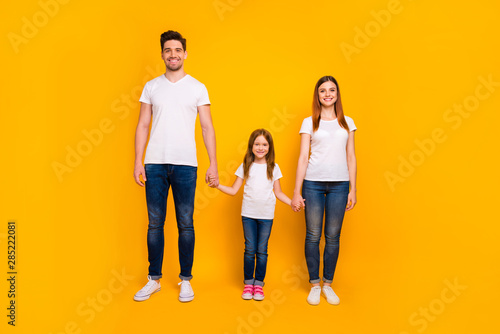 Full length body size view of three nice-looking attractive charming stylish trendy cheerful person holding hands spending weekend isolated over bright vivid shine yellow background