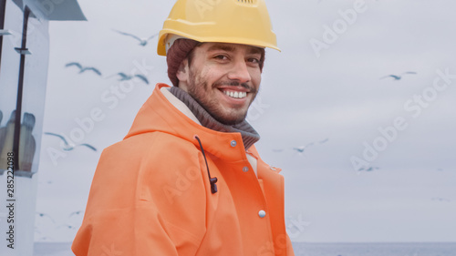 Portrait of Dressed in Bright Protective Coat Smiling Fisherman on Commercial Fishing Boat.