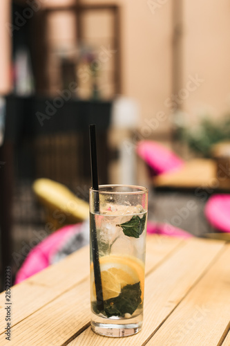 glass of cold lemonade with mint and lemon on wooden background