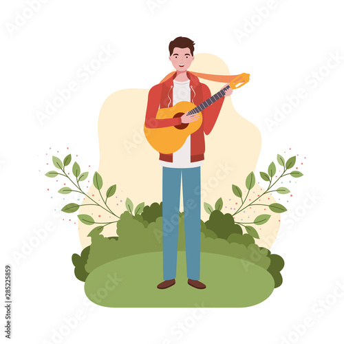 man with acoustic guitar and branches and leaves in the background photo