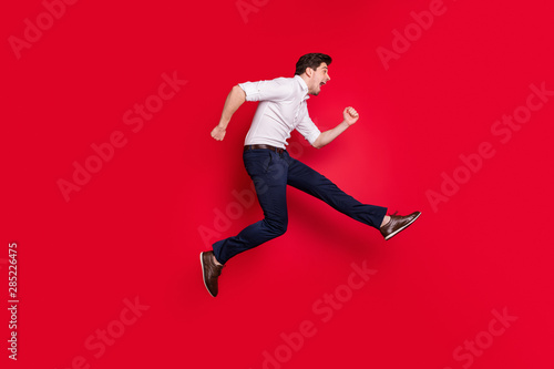 Full length body size photo of urgent hurrying running man going towards something he is interested in while isolated with red background