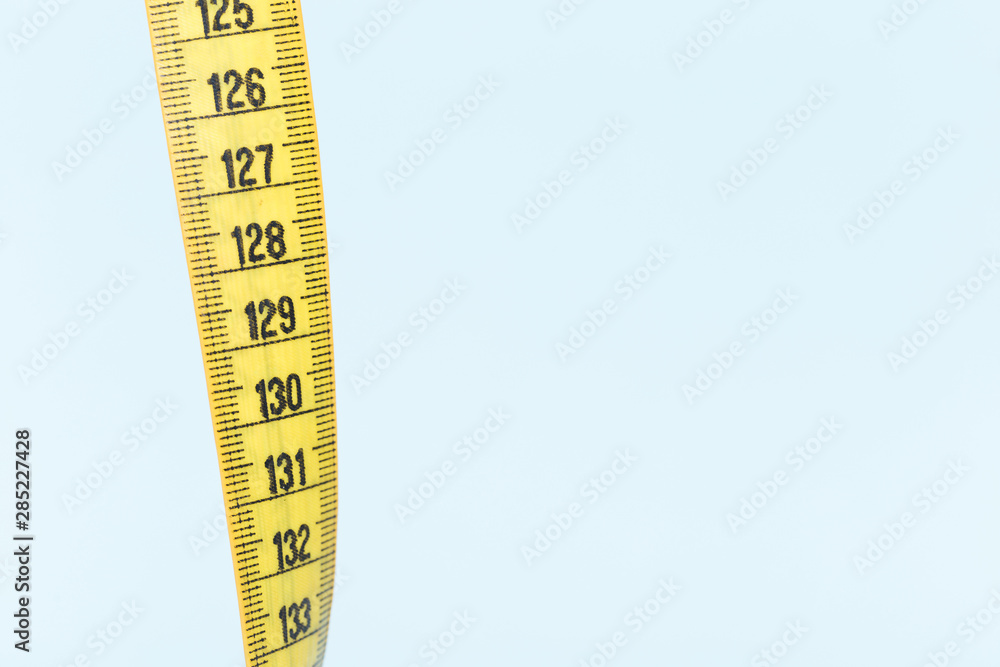 Yellow tape measure on blue background Yellow tape measure on blue background