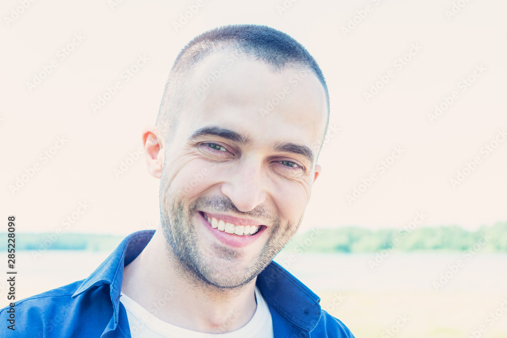 Attractive young man in Park in summer, man smiling and looking in the camera, portrait, close up, toned Attractive young man in Park in summer, man smiling and looking in the camera, portrait, close up, toned