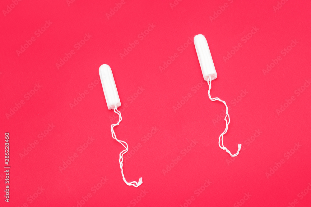Two tampons on a red background, close up, copy space, top view, menstrual period concept Two tampons on a red background, close up, copy space, top view, menstrual period concept